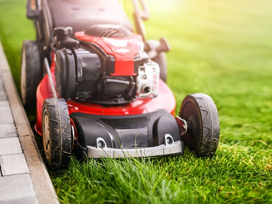 Lawnmoverongreengrassinmoderngarden. Kopie